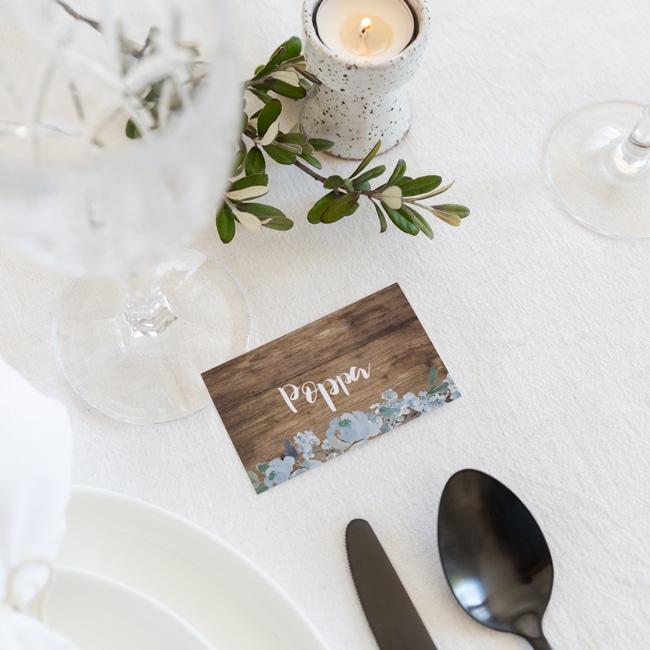 Placecard sitting on white rose, napkin and plate