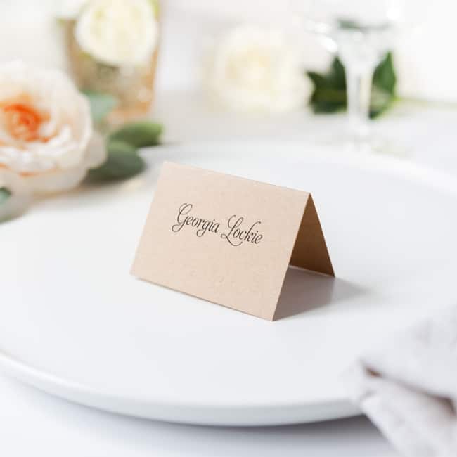 folded kraft brown card with guest name sitting on wedding reception table on a plate