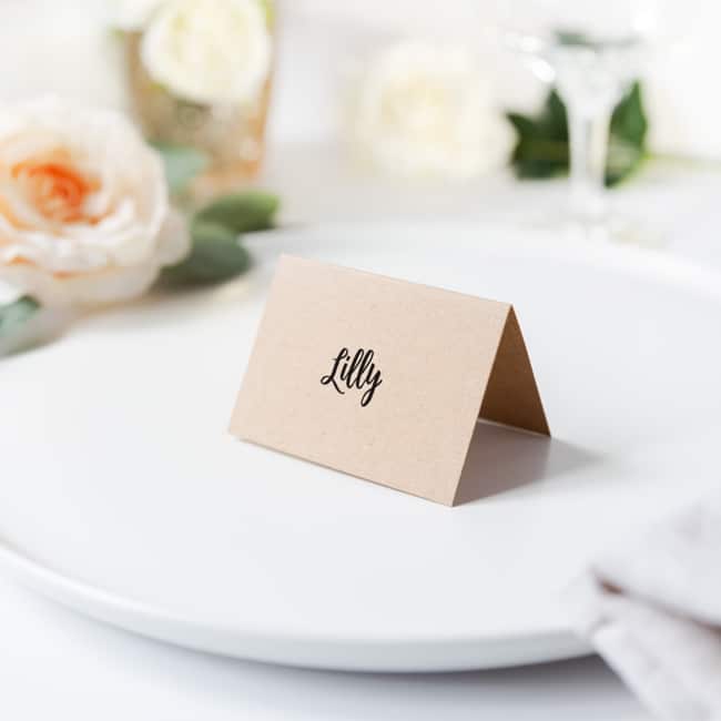 Guest name printed on folded kraft card place setting sitting on plate
