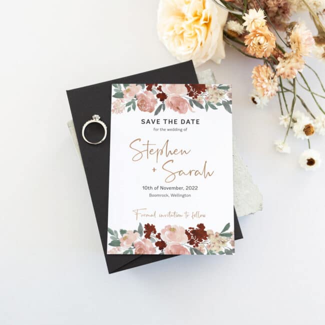 save the date card next to flowers and wedding ring