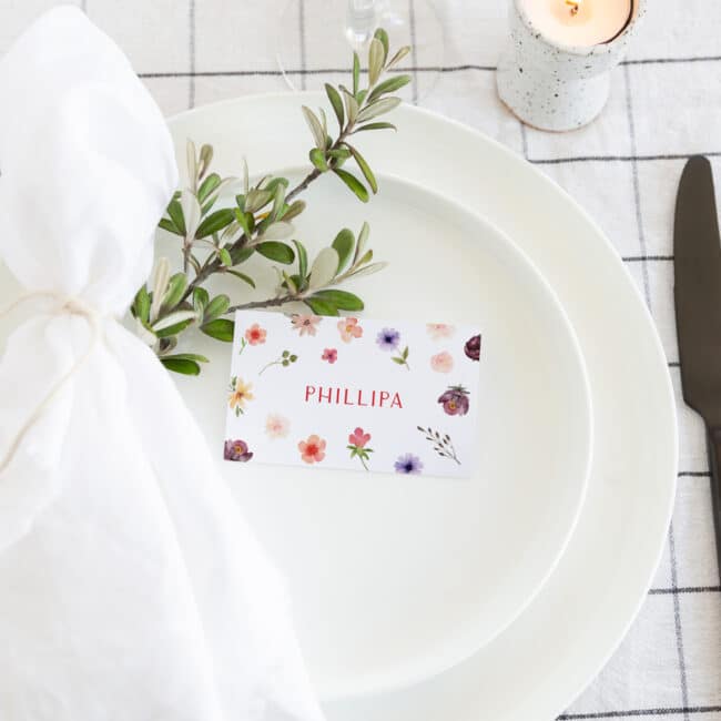 flat placecard on dinner plate with greenery and napkin