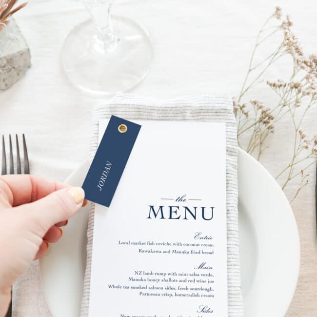 Traditional Navy monogram menu with guest name tag attached with gold rivet