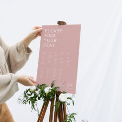 Person placing foam board seating plan on easel with floral decorations
